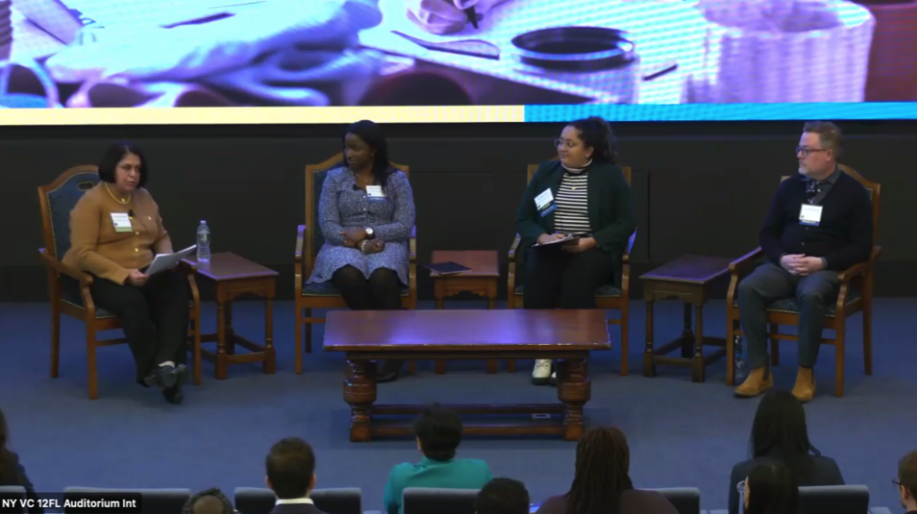An image from the panel livestream depicts four speakers on a stage at the Federal Reserve Bank of New York. The three panelists look left, toward the session’s moderator. 

